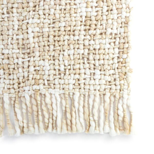 Detail view of the fringe on a loosely woven cream fringed blanket.